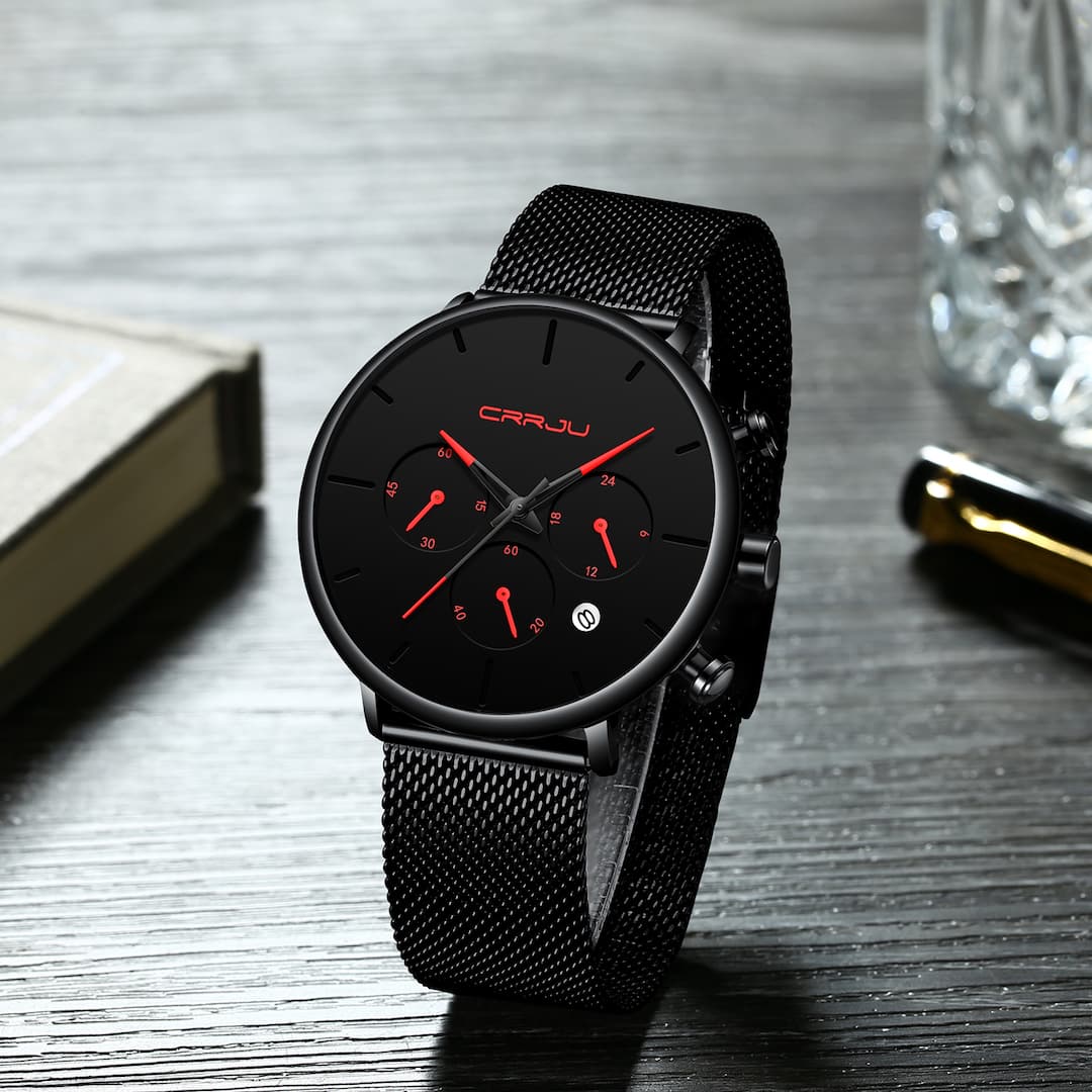 Muški ručni sat Crrju Chrono Red s crvenim kazaljkama i kronografima, položen na knjigu uz kristalnu čašu.