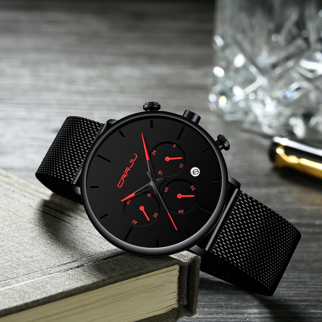 Muški ručni sat Crrju Chrono Red s crvenim kazaljkama i kronografima, postavljen na stol uz knjigu.