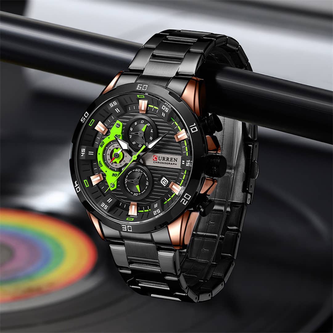 Muški ručni sat Curren Chronograf Green s metalnim remenom, obješen na metalnu šipku.