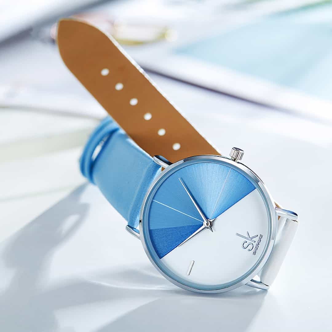 Ženski ručni sat SK Shengke DuoTone Leather Blue sa svijetlim remenom, prikazan na svijetloj površini.